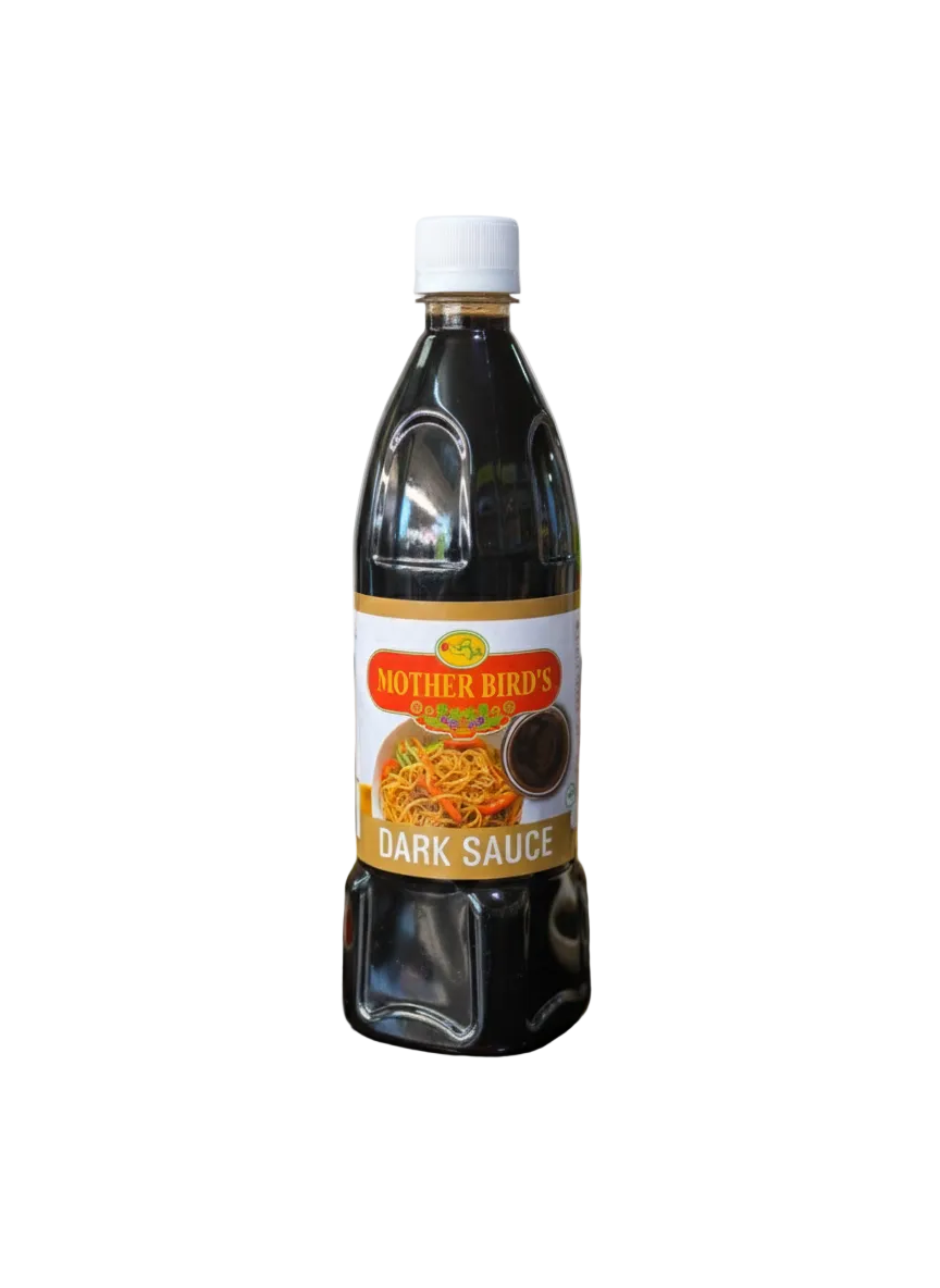 Bottle of Motherbird's Dark Sauce on a reflective surface with ingredients in the background
